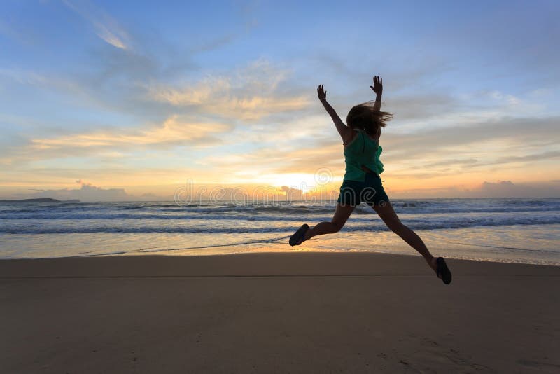 Salto feliz del viajero de la mujer en la playa con salida del sol foto de archivo Salto feliz del viajero de la mujer en la playa con salida del sol foto de archivo