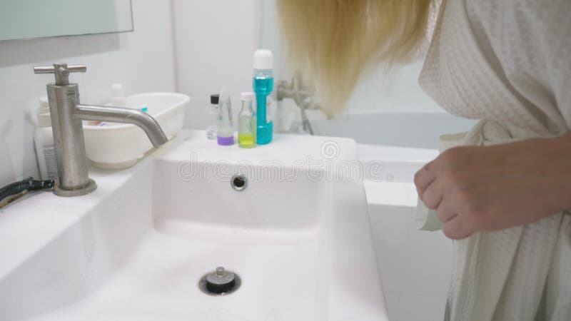 Salud del pelo, concepto de la pérdida de pelo Mujer que se peina el cabello seco dañado rubio en el cuarto de baño