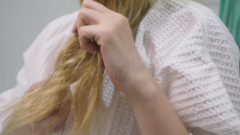 Salud del pelo, concepto de la pérdida de pelo Mujer que se peina el cabello seco dañado rubio en el cuarto de baño