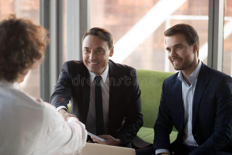 Saludo sonriente del candidato de trabajo del apret?n de manos de los encargados de la hora con ?xito foto de archivo Saludo sonriente del candidato de trabajo del apret?n de manos de los encargados de la hora con ?xito foto de archivo