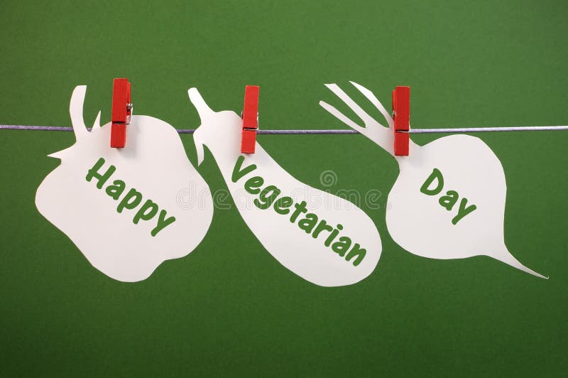Salutation végétarienne heureuse de message de jour écrite à travers les cartes végétales pendant des chevilles sur une ligne