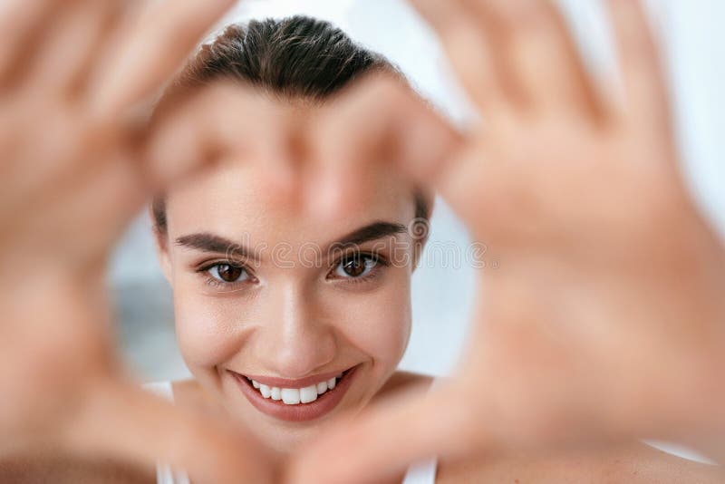 Salute dell'occhio Bello fronte della donna con le mani a forma di del cuore bellezza fotografie stock