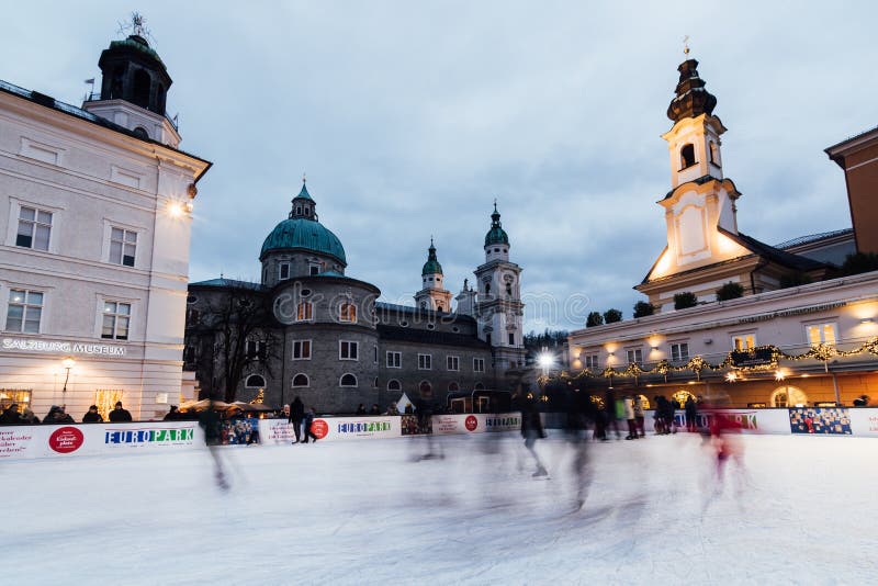 SALZBURG ÖSTERRIKE - DECEMBER 2018: folket som åker skridskor på isisbanan på gammal stadjul, marknadsför royaltyfri bild SALZBURG ÖSTERRIKE - DECEMBER 2018: folket som åker skridskor på isisbanan på gammal stadjul, marknadsför royaltyfri bild