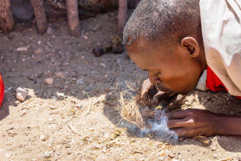 Masai warrior are making a fire with dry grass on the ground royalty free stock image Masai warrior are making a fire with dry grass on the ground royalty free stock image