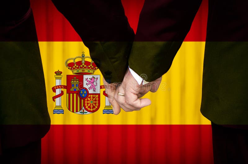 Two gay men stand hand in hand before a marriage altar featuring an overlay of the flag colors of Spain, having just been legally married under the Same-Sex Marriage legislation of that country. Two gay men stand hand in hand before a marriage altar featuring an overlay of the flag colors of Spain, having just been legally married under the Same-Sex Marriage legislation of that country.