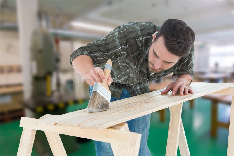 Samengesteld beeld van arbeider die borstel op houten plank gebruiken stock fotografie Samengesteld beeld van arbeider die borstel op houten plank gebruiken stock fotografie