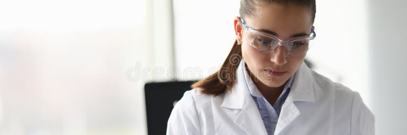 Portrait of young scientist going through laboratory report. Worker holding journal with latest results. Lab assistant in white medical gown. Investigation and analysis concept. Portrait of young scientist going through laboratory report. Worker holding journal with latest results. Lab assistant in white medical gown. Investigation and analysis concept