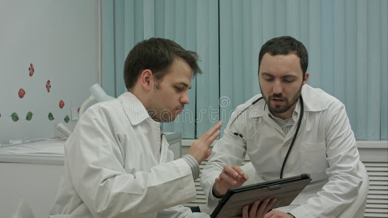 Samiec fabrykuje dopatrywanie na pastylka komputerze osobistym i dyskutować wynika zdjęcie stock Samiec fabrykuje dopatrywanie na pastylka komputerze osobistym i dyskutować wynika zdjęcie stock