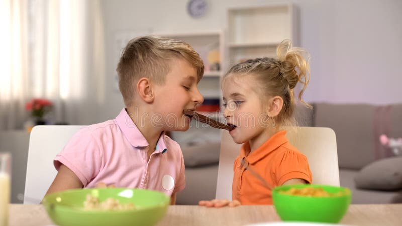 Samiec i kobiety dzieciaki je czekolad? wp?lnie, brata udzielenia cukierki siostrzani zdjęcia stock Samiec i kobiety dzieciaki je czekolad? wp?lnie, brata udzielenia cukierki siostrzani zdjęcia stock