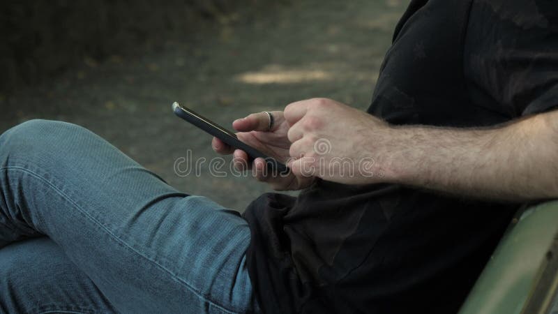 Samiec ręki używać smartphone w parku TARGET457_1_ na ?awce