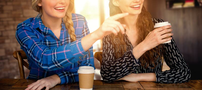 Women pointing forward in cafe against empty chairs and tables. Women pointing forward in cafe against empty chairs and tables