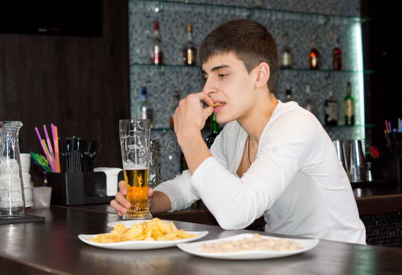 Sammanträde för ung man som dricker och äter på en bar