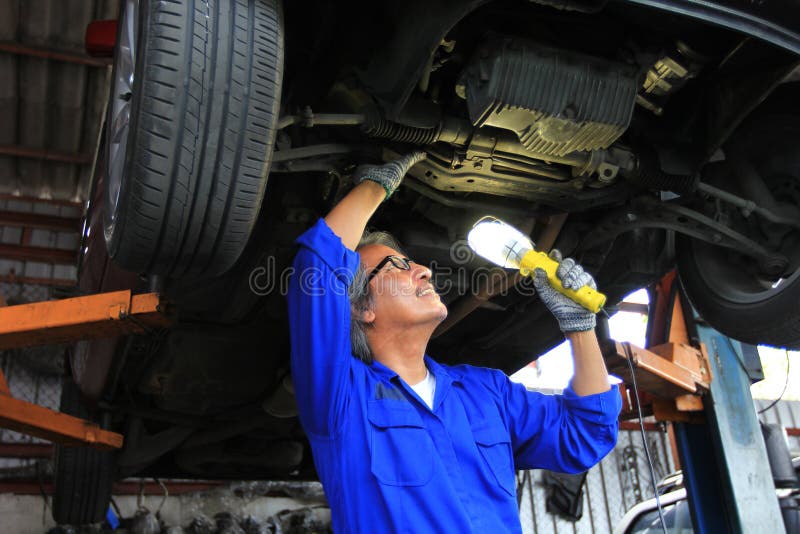 Samochodowy mechanik egzamininuje samochód używać latarkę w auto remontowej usłudze obrazy royalty free Samochodowy mechanik egzamininuje samochód używać latarkę w auto remontowej usłudze obrazy royalty free