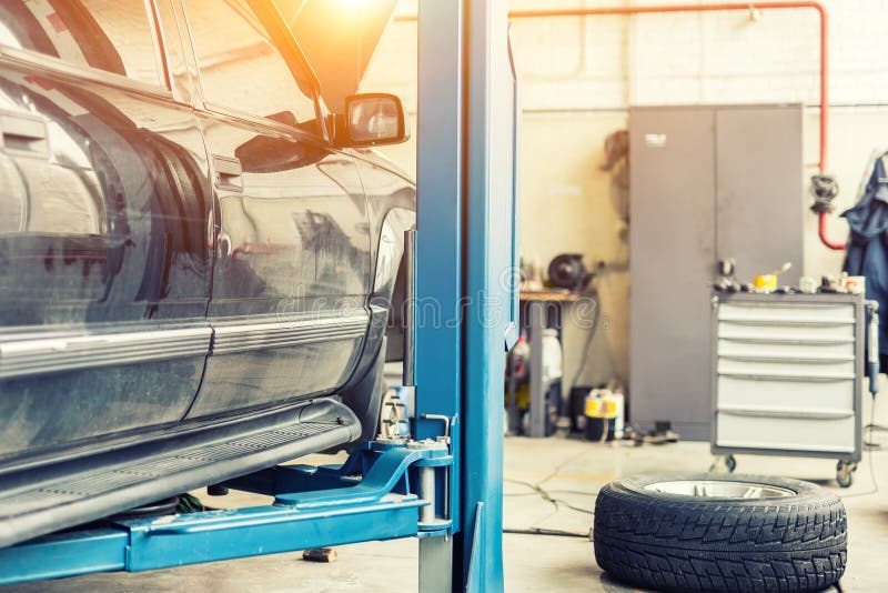 Samochodowy usługowy centrum Stary ośniedziały offroad SUV pojazd podnoszący na dźwignięciu przy utrzymanie stacją Samochodu czek zdjęcie stock Samochodowy usługowy centrum Stary ośniedziały offroad SUV pojazd podnoszący na dźwignięciu przy utrzymanie stacją Samochodu czek zdjęcie stock