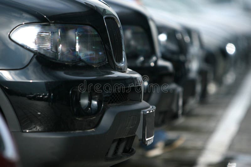 Row of cars in a car park, focus on the closest one. Row of cars in a car park, focus on the closest one.