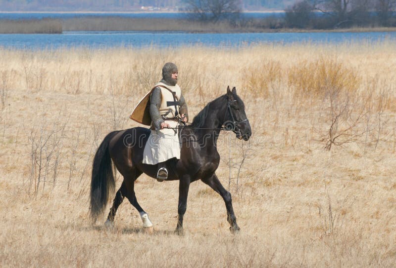 SAMOLVA, PSKOVSKAYA OBLAST, RUSSIA - APRIL 22: unindentified horseback rider on a horse of historical reconstruction of the Batle on the Ice dressed in knightly armor and medieval clothes on April 22, 2012 in village Samolva near Pskov, Russia. SAMOLVA, PSKOVSKAYA OBLAST, RUSSIA - APRIL 22: unindentified horseback rider on a horse of historical reconstruction of the Batle on the Ice dressed in knightly armor and medieval clothes on April 22, 2012 in village Samolva near Pskov, Russia.