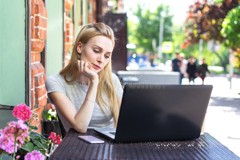 Samozatrudniający się freelancer Kaukaska kobieta pracuje z jej laptopem w restauracyjnym tarasie w ulicie w słonecznym dniu i te zdjęcie stock Samozatrudniający się freelancer Kaukaska kobieta pracuje z jej laptopem w restauracyjnym tarasie w ulicie w słonecznym dniu i te zdjęcie stock