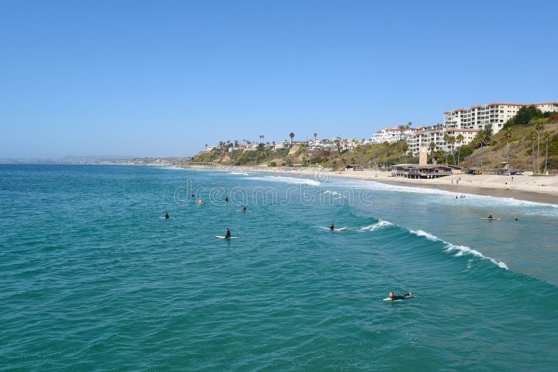 The beach and coastline with surfers and sunbathers seen from the pier in the South Orange. SAN CLEMENTE, CALIFORNIA - 18 OCT 2019: The beach and coastline with royalty free stock photo The beach and coastline with surfers and sunbathers seen from the pier in the South Orange. SAN CLEMENTE, CALIFORNIA - 18 OCT 2019: The beach and coastline with royalty free stock photo
