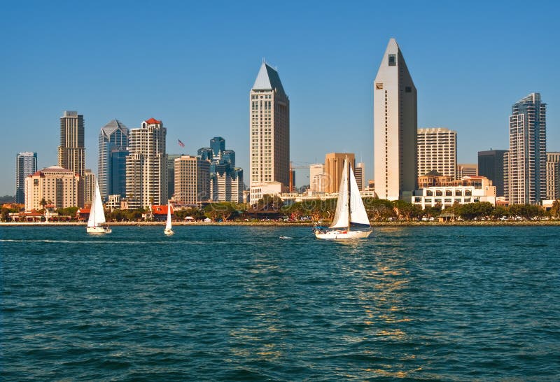 La skyline di San Diego, tra cui il Seaport Village, come si è visto dalla baia, con barche a vela in primo piano, un luminoso cielo azzurro, l'azzurro dell'acqua al giorno.