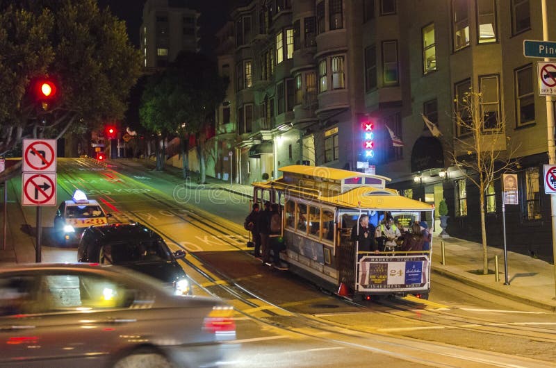 Night view of the traditional and historic cable car in San Francisco, California, United States. A view of the street car and people riding it up the steep hill in the city. Night view of the traditional and historic cable car in San Francisco, California, United States. A view of the street car and people riding it up the steep hill in the city.