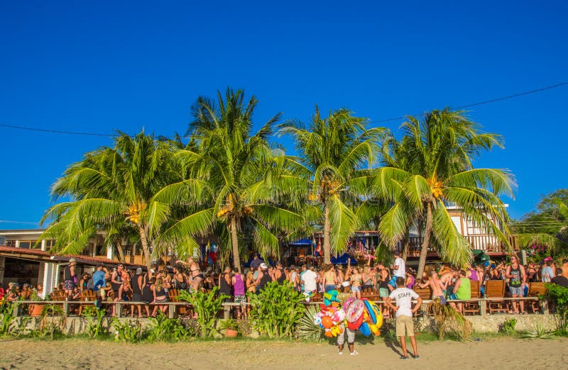 San Juan del Sur, Nicaragua - May 11, 2018: Crowd of people wearing underwear and fresh clothes at outdoor party in a sunny day, under some palm trees in San Juan del Sur in Nicaragua. San Juan del Sur, Nicaragua - May 11, 2018: Crowd of people wearing underwear and fresh clothes at outdoor party in a sunny day, under some palm trees in San Juan del Sur in Nicaragua.