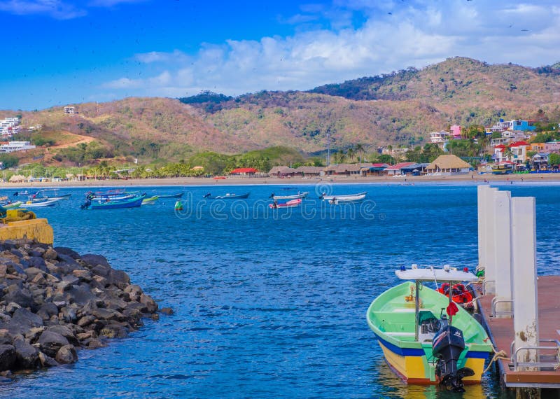 San Juan del Sur, Nicaragua - May 11, 2018: View of some boats on the pier of San Juan Del sur on the ocean coast in Nicaragua in a beautiful sunny day and gorgeous blue water and sky. San Juan del Sur, Nicaragua - May 11, 2018: View of some boats on the pier of San Juan Del sur on the ocean coast in Nicaragua in a beautiful sunny day and gorgeous blue water and sky.