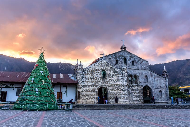 San Juan la Laguna, Lake Atitlan, Guatemala - December 16, 2018: Artificial Christmas tree outside Catholic church against sunset sky in lakeside village San Juan la Laguna, Guatemala, Central America. San Juan la Laguna, Lake Atitlan, Guatemala - December 16, 2018: Artificial Christmas tree outside Catholic church against sunset sky in lakeside village San Juan la Laguna, Guatemala, Central America