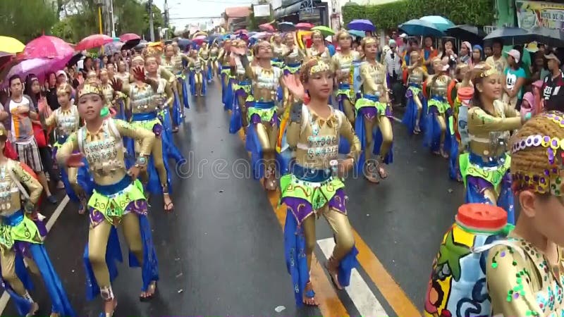 Young boys and girls in ornate coconut costume dance along the street, a festival to honor a patron saint