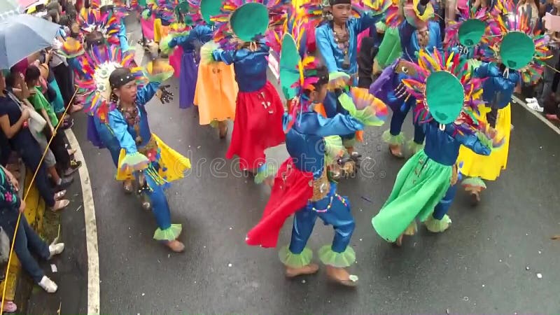 Young boys and girls in ornate coconut costume dance along the street, a festival to honor a patron saint