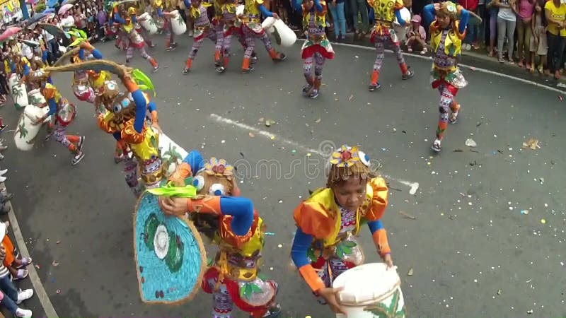 Young boys and girls in ornate coconut costume dance along the street, a festival to honor a patron saint