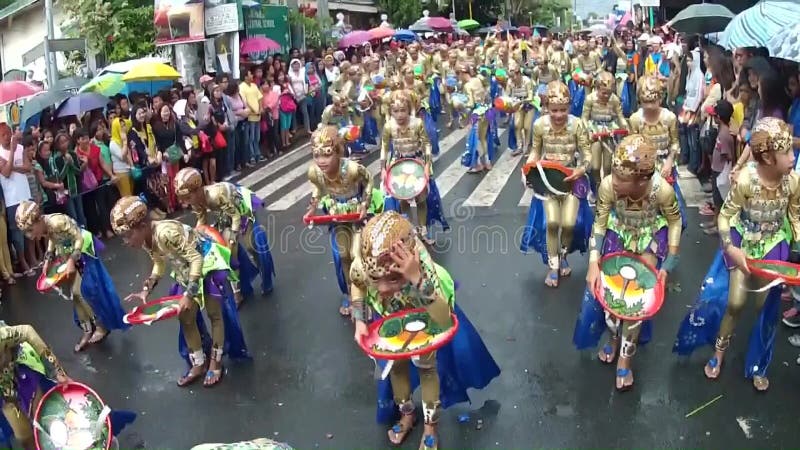 Young boys and girls in ornate coconut costume dance along the street, a festival to honor a patron saint