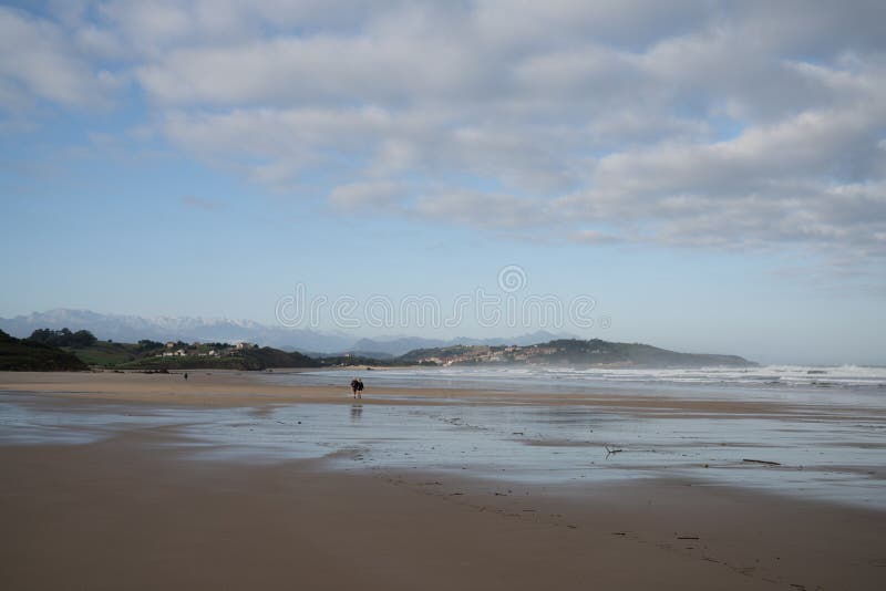 Senior citizen couple enjoys a walk on a wild and rocky and sandy beach at low tide