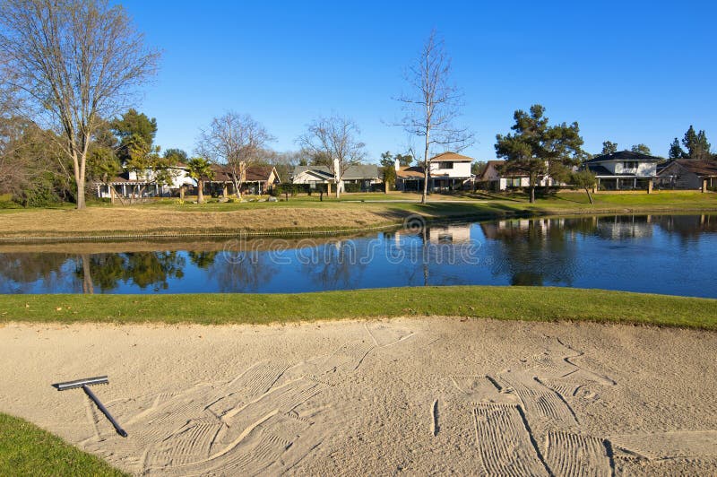 Sand bunker on the golf course with trees and pond