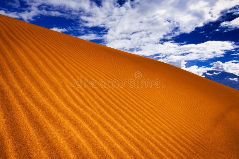 Sand dune in desert under blue sky