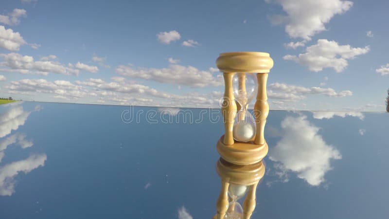 Sandglass en el espejo y las nubes indican, concepto del tiempo, timelapse, 4K