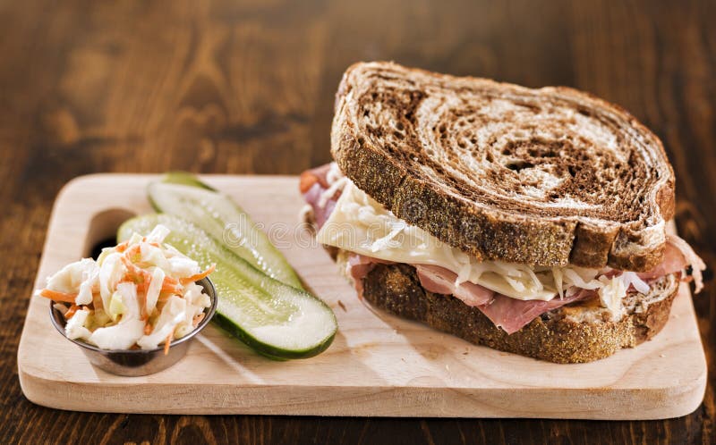 Close up photo of a single reuben sandwich with kosher dill pickle and coleslaw. Close up photo of a single reuben sandwich with kosher dill pickle and coleslaw