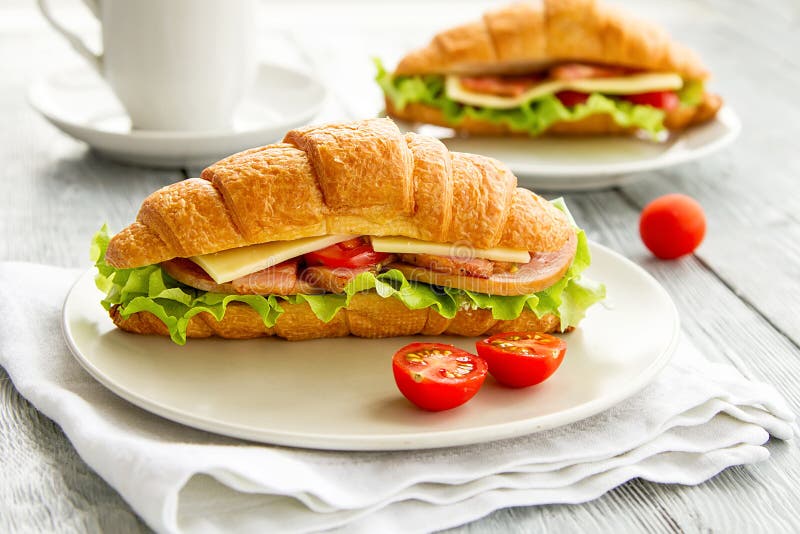 Sanduíche delicioso do croissant na tabela de madeira Pequeno almoço saudável foto de stock Sanduíche delicioso do croissant na tabela de madeira Pequeno almoço saudável foto de stock