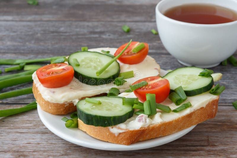 Sanduíches com queijo creme, tomates de cereja, pepinos e as cebolas verdes imagem de stock Sanduíches com queijo creme, tomates de cereja, pepinos e as cebolas verdes imagem de stock