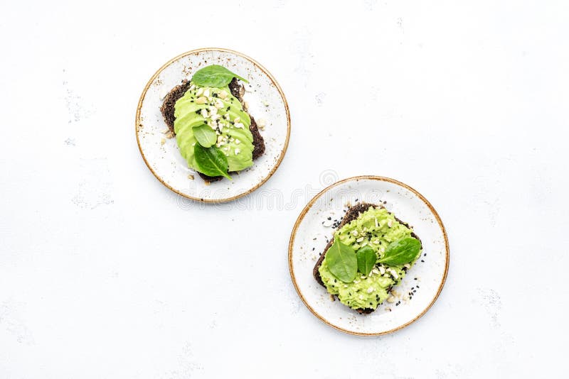 Sandviș cu avocado sau pâine prăjită pe pâine de secară cu nuci de cajou zdrobite cu spanac și semințe de susan pe fond alb de mas royalty free stock photo