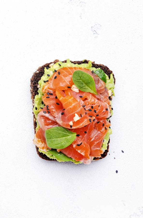 Sandviș cu somon avocado sau pâine prăjită pe pâine de secară cu nuci de cajou zdrobite cu spanac și semințe albe pentru masă stock photo