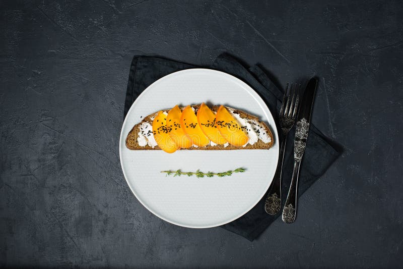 Sandwich avec le kaki et fromage à pâte molle sur un fond noir avec l'espace pour le texte image stock Sandwich avec le kaki et fromage à pâte molle sur un fond noir avec l'espace pour le texte image stock