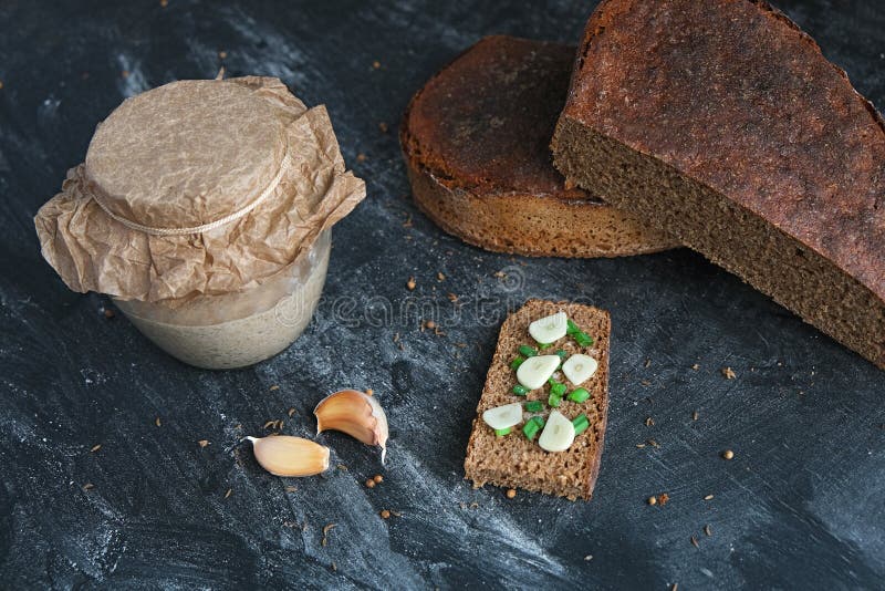 Sandwich des Handwerkerbrotes mit Zwiebelschnittlauch- und -nelkenknoblauchsauerteig im Glas- und Gewürzen Schnittlaibroggenbrot m lizenzfreie stockbilder