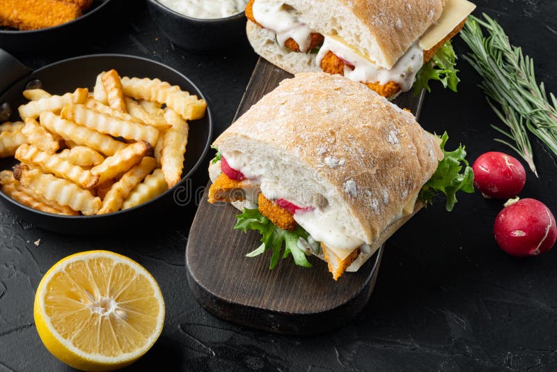 Sandwich with Fish Sticks, on wooden cutting board, on black background stock photo