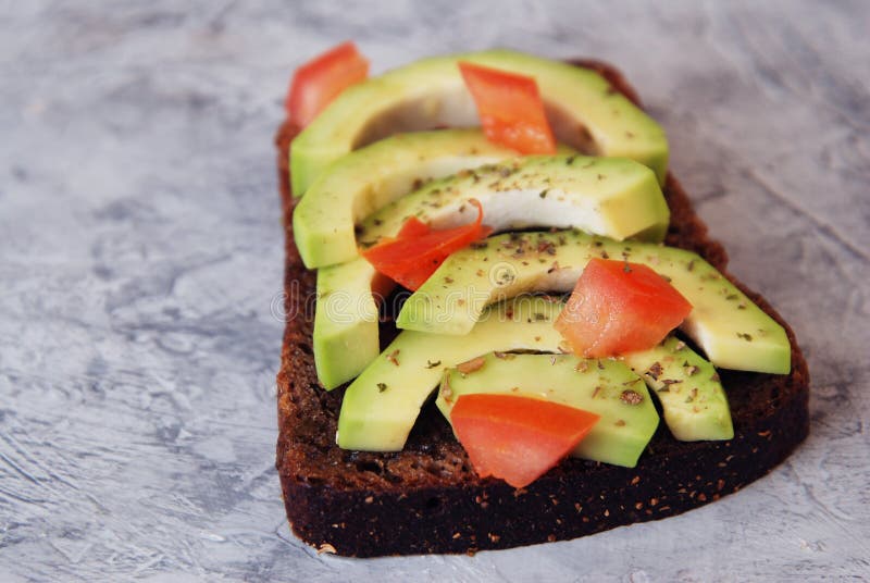 Sandwich mit Avocado und Tomaten - gesundes Frühstückskonzept lizenzfreie stockbilder Sandwich mit Avocado und Tomaten - gesundes Frühstückskonzept lizenzfreie stockbilder