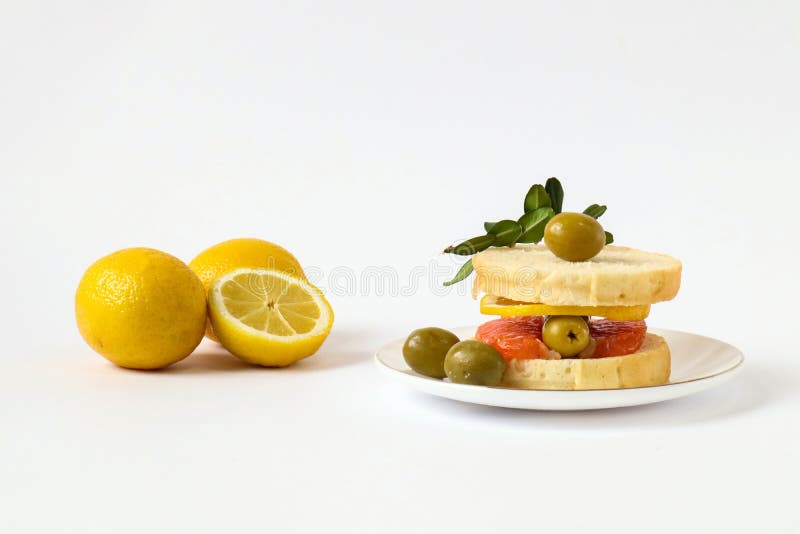 Sandwich with Red Fish, Olives, Lemon on the Background of Lemons, White Background, Side View