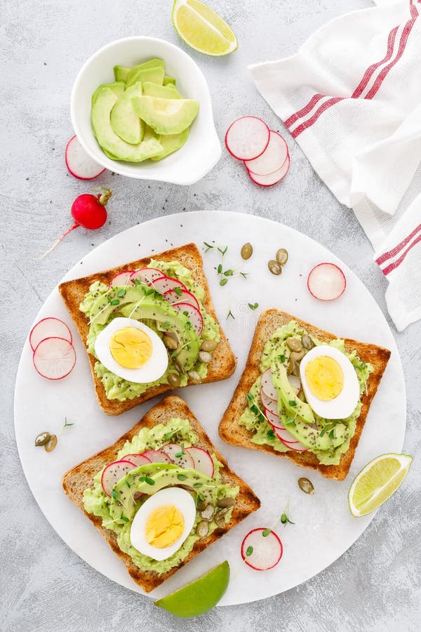 Sandwiche mit Avocadoguacamolen, frischem Rettich, gekochtem Ei, chia und Kürbiskernen Köstliche und gesunde Anlage-b des Diätfrü stockbild Sandwiche mit Avocadoguacamolen, frischem Rettich, gekochtem Ei, chia und Kürbiskernen Köstliche und gesunde Anlage-b des Diätfrü stockbild
