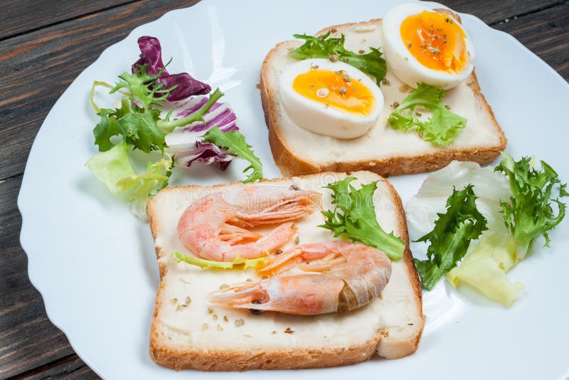 Sandwiche mit Garnele, Ei, Basilikum, Salat, Brot auf hölzernem Hintergrund Köstliche kalte Snäcke Vegetarische Mahlzeiten Gesund lizenzfreies stockbild Sandwiche mit Garnele, Ei, Basilikum, Salat, Brot auf hölzernem Hintergrund Köstliche kalte Snäcke Vegetarische Mahlzeiten Gesund lizenzfreies stockbild