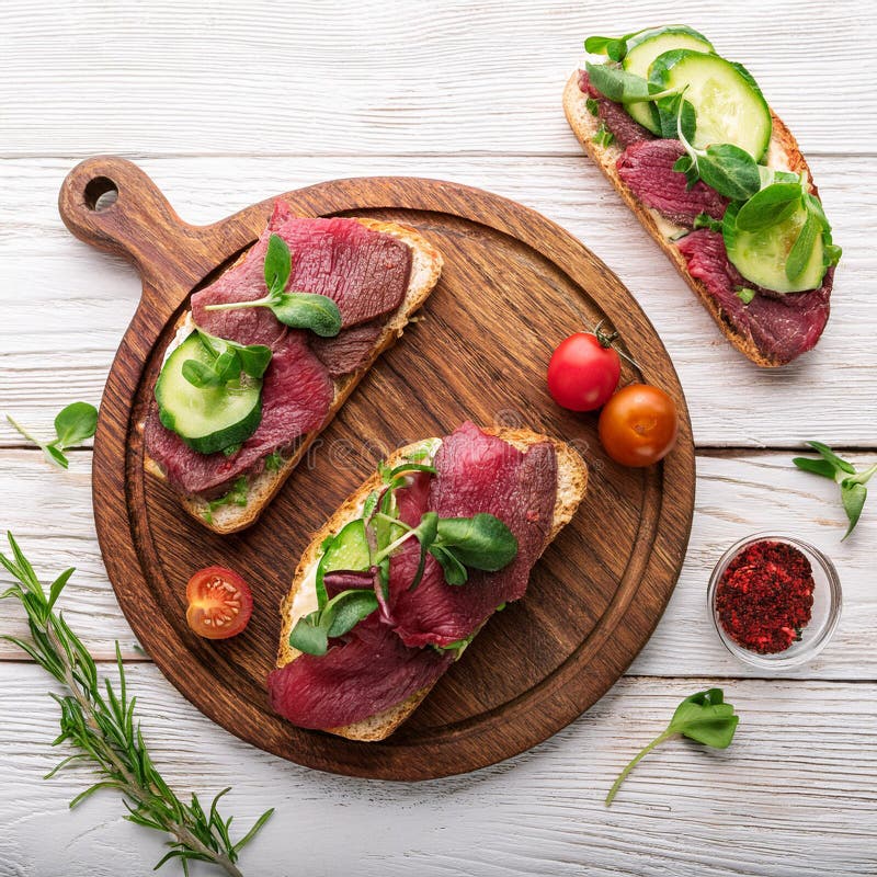 Sandwiches with beef, fresh vegetables and herbs on rustic wooden chopping board over white wood backdrop, top view. stock illustration