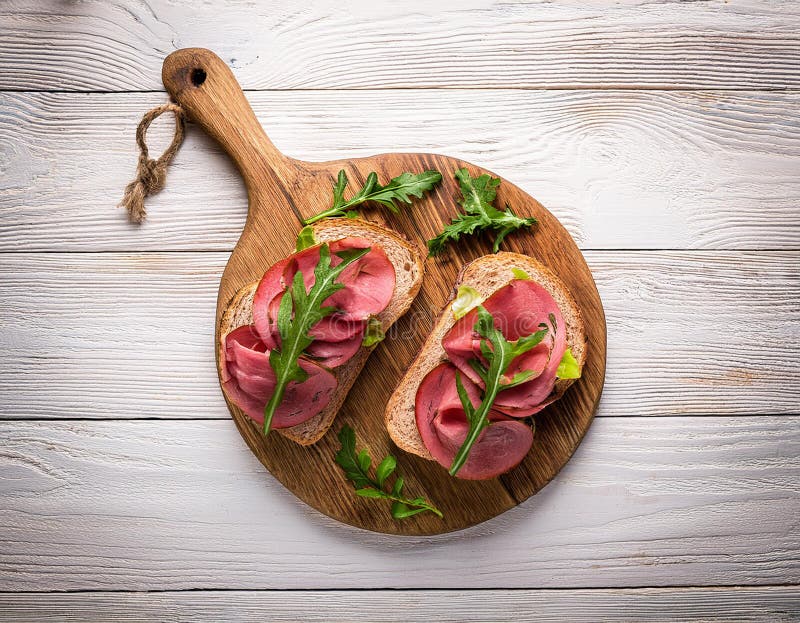Sandwiches with beef, fresh vegetables and herbs on rustic wooden chopping board over white wood backdrop, top view. royalty free illustration