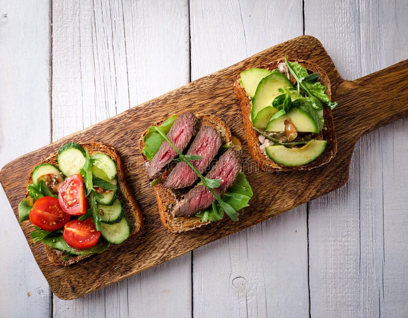Sandwiches with beef, fresh vegetables and herbs on rustic wooden chopping board over white wood backdrop, top view. royalty free illustration